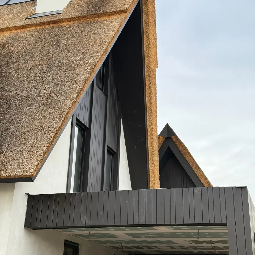 Detail van een rieten dak met zwart houten gevel